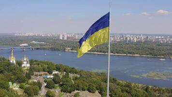 Aerial view of The largest flag of Ukraine is flying against the backdrop of the city of Kyiv and the Dnieper River. 4K video