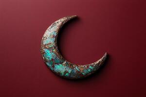 A crescent moon design with a turquoise and bronze texture on a red background photo
