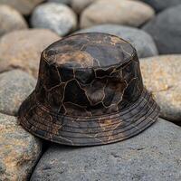 A stylish bucket hat with a unique cracked pattern resting on rocks photo