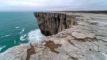 Waves crash against the cliffside on a cloudy day photo