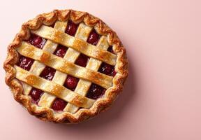 A delicious cherry pie with lattice crust on a pink background photo