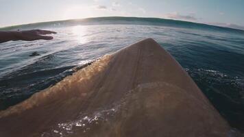 Surfer paddles on surfboard and duck dive under waves in ocean. First-person view and crashing waves video