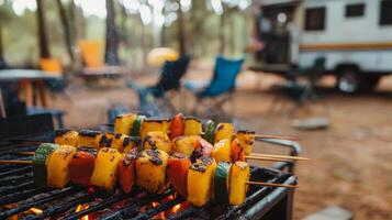 Friends gather around a campfire, savoring grilled vegetable skewers made from fresh peppers and zucchini. The relaxing atmosphere is complemented by a cozy camper in the background. photo