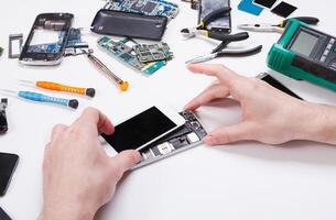 Electronics repair service. Repairman disassembling smartphone for inspecting. Technician fixing broken phone, copy space for text photo