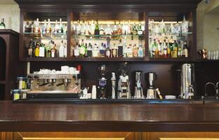 Bar counter with alcohol bottles assortment. Barroom in restaurant, hotel, pub copy space. Cafe background photo