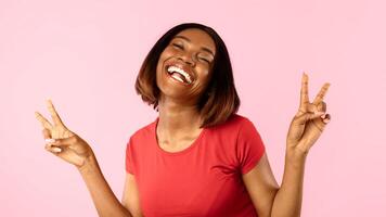 Happy Black Lady Gesturing Victory Symbol With Both Hands Smiling To Camera Standing On Yellow Studio Background. Portrait Of Cheerful Woman Showing V-Sign, Peace Gesture Panorama photo