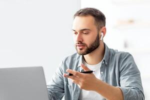 Learning English online. Focused male teacher giving foreign language lesson on web using laptop. Millennial tutor explaining grammar rules to students on internet during covid lockdown photo