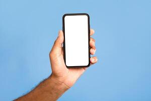 Amazing mobile app. Unrecognizable African American man showing cellphone with mockup, advertising application or website, promoting online product or service over blue background, closeup photo