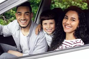 Portrait Of Happy Arab Family Riding Car Together, Cheerful Middle Eastern Parents With Little Son Sitting In Modern Vehicle And Smiling At Camera Through Window, Enjoying Summer Trip, Closeup photo
