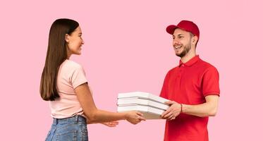 Pizza Delivery. Courier Guy Giving Pizzas Boxes To Lady Standing On Yellow Background In Studio. Italian Restaurant Delivering Service, Takeaway Concept. Full Length photo