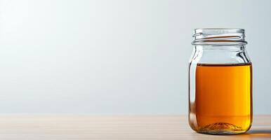 A clear glass jar filled with golden organic honey sits on a wooden surface. This natural product represents sustainable beekeeping and promotes healthy eating choices. photo