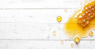 Honey drizzles and splashes on a rustic white wooden surface, showcasing its rich golden color. The liquid forms droplets around a honeycomb, creating a visually appealing arrangement. photo