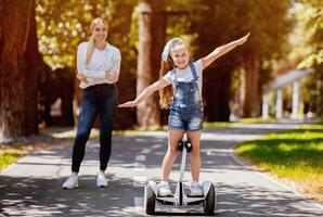 Little Girl Riding Segway Having Fun Spending Weekend With Mother In Park Outdoor. Selective Focus photo