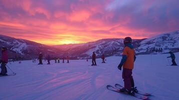 A group of skiers gathers on a ski slope as the sky fills with vibrant colors during sunset, creating a picturesque winter atmosphere in the mountains. photo
