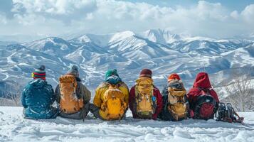 A group of six hikers sits side by side on a snowy mountain slope, gazing out at majestic peaks under a clear blue sky. The bright sun casts shadows across the landscape. photo