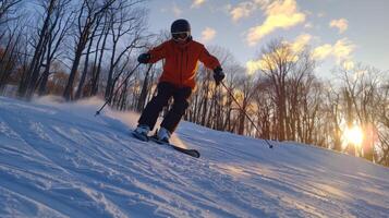 A skier in an orange jacket gracefully descends a snow covered slope as the sun sets, casting a warm glow through the trees that line the path, creating a picturesque winter scene. photo