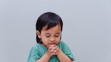 Asian boy praying to God with hands held together photo