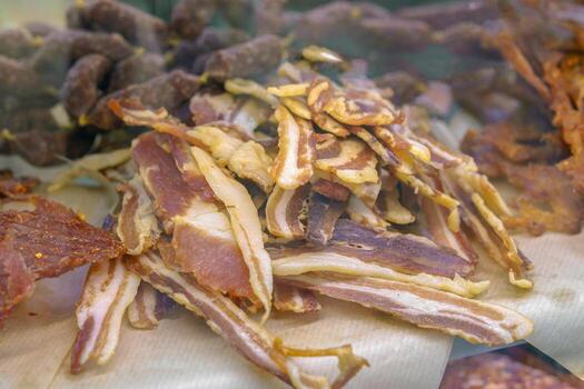 A pile of bacon strips on a table. The bacon is cut into strips and is spread out on a piece of paper photo