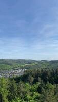 Panoramic mountain view with forest, village, and wind turbines under clear sky video