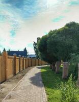 A walkway with a wooden fence and brick walkway photo