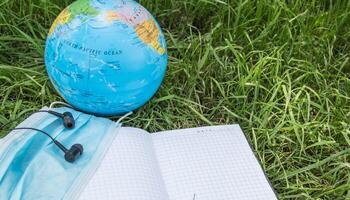 A globe, a mask and a notebook on the grass photo
