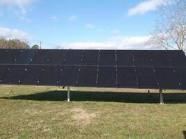 a large solar array on a field with trees in the background photo