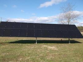 This is a large solar array on a field with trees in the background photo