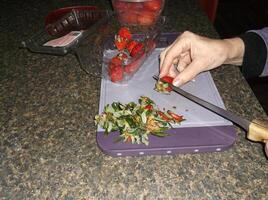 a person cutting up strawberries on a cutting board photo