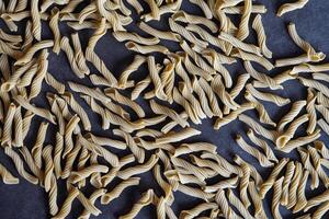 A composition of tubular pasta that is scattered on the table. Pasta is scattered on a black surface and photographed close-up. photo