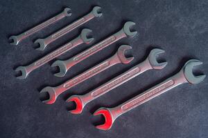 Visual effect with a red sheen on metal open-end wrenches. Seven wrenches of different sizes, made of durable chrome vanadium. photo
