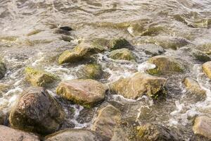 Sea stones and waves on the beach. Summer background. photo