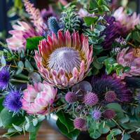 A stunning bouquet featuring a large king protea in shades of pink and purple thistles creates a vivid display of floral artistry. Each blossom adds depth and texture, celebrating nature's splendor photo