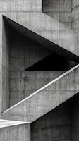 An abstract background features a textured concrete surface with sharp geometric shapes and angles. The interplay of light and shadows enhances the modern aesthetic photo