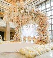 A huge floral installation made of white and pastel flowers. The installation is located in an elegant hotel lobby, surrounded by modern architecture photo