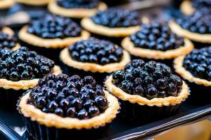 A stunning display of assorted blackberry tarts waits to delight at a dessert table. Each tart is piled high with juicy blackberries, creating an eye-catching treat for guests photo
