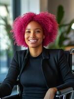 Happy disabled woman in a wheelchair with pink hair smiles in a vibrant, diverse workplace, capturing a moment of joy and inclusion photo