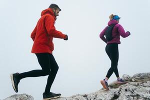 Trail running couple man and woman running on a mountain path photo