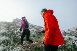 Trail running couple man and woman running on a mountain path photo