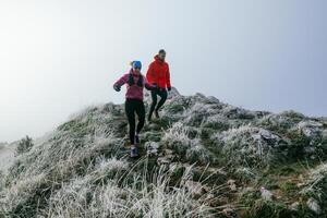 Trail running couple man and woman running on a mountain path photo