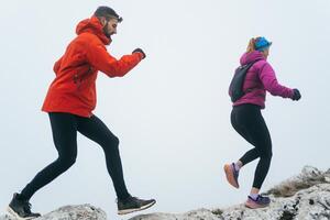 Trail running couple man and woman running on a mountain path photo