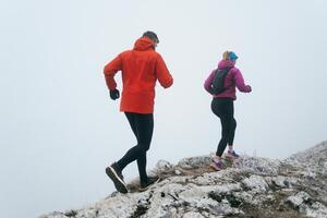 Trail running couple man and woman running on a mountain path photo