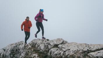 Trail running couple man and woman running on a mountain path photo