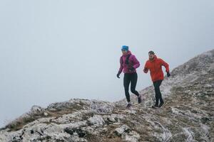 Trail running couple man and woman running on a mountain path photo