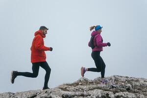 Trail running couple man and woman running on a mountain path photo