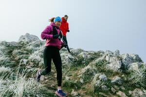 Trail running couple man and woman running on a mountain path photo