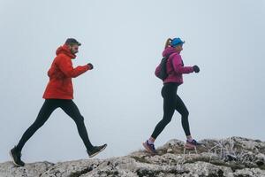 Trail running couple man and woman running on a mountain path photo
