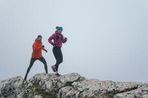 Trail running couple man and woman running on a mountain path photo
