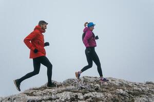 Trail running couple man and woman running on a mountain path photo