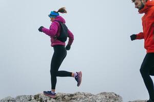 Trail running couple man and woman running on a mountain path photo