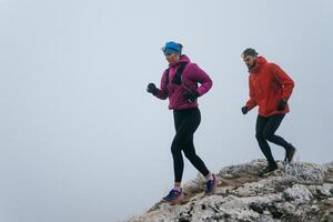 Trail running couple man and woman running on a mountain path photo